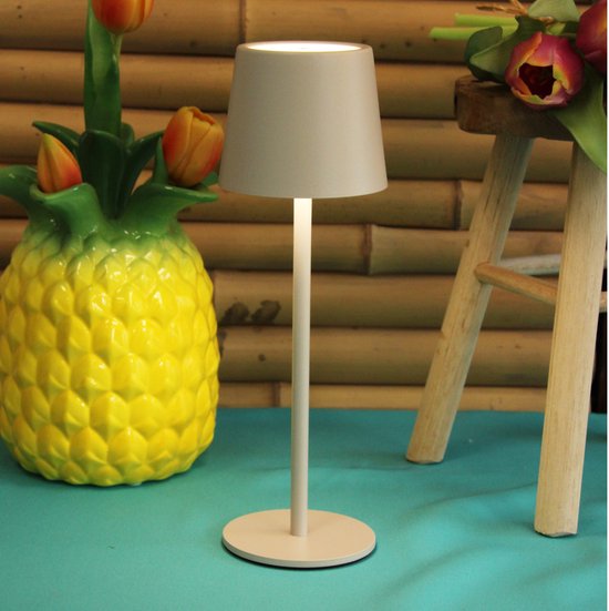 Beige tafellamp met grijze kap, naast een decoratieve ananas en tulpen.