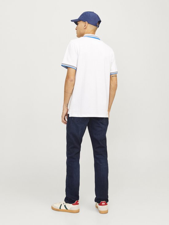 Man met witte polo, donkere jeans en cap.