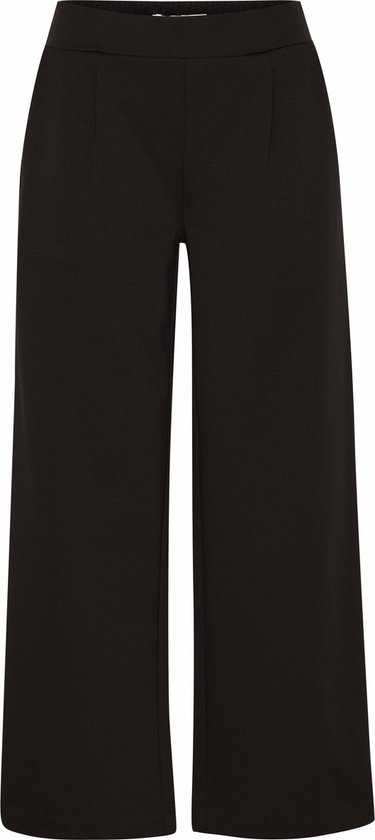 Pantalon noir court et ample, avec plis marqués et ceinture élastique.