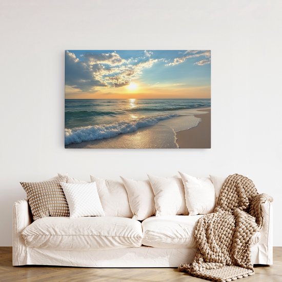 Canvas schilderij met zonsondergang aan zee, hangend boven een lichte bank met gebreide deken.