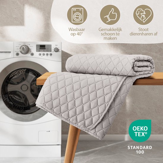 Lichtgrijze, gewatteerde sprei bij een wasmachine. Iconen tonen wasbaar op 40°, makkelijk schoon te maken en stoot dierharen af.