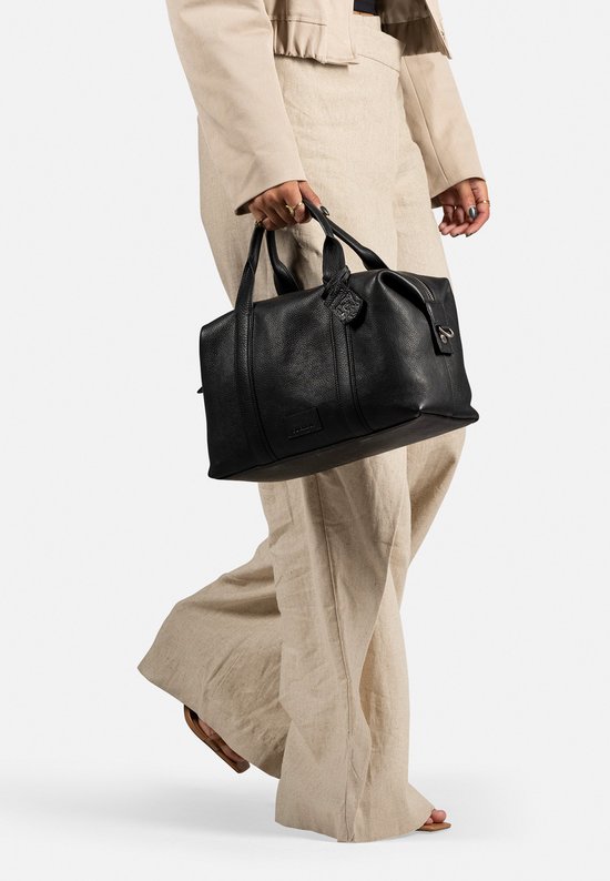 Vrouw met beige outfit draagt een zwarte leren Burkely bowler tas.