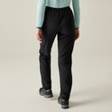 Vrouw loopt weg, draagt een lichtblauwe gestreepte longsleeve en zwarte hikingbroek.