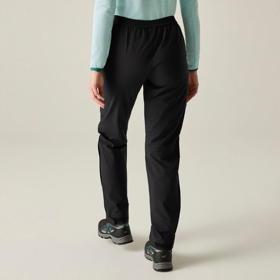 Vrouw loopt weg, draagt een lichtblauwe gestreepte longsleeve en zwarte hikingbroek.