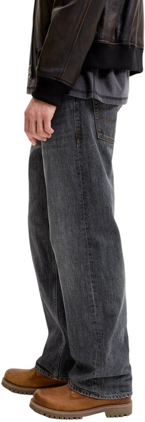 Zijaanzicht van model in grijze jeans met bruine boots.