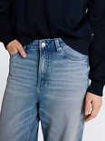 Detail van de tailleband van een wijde, lichtblauwe jeans met lichte wassing.