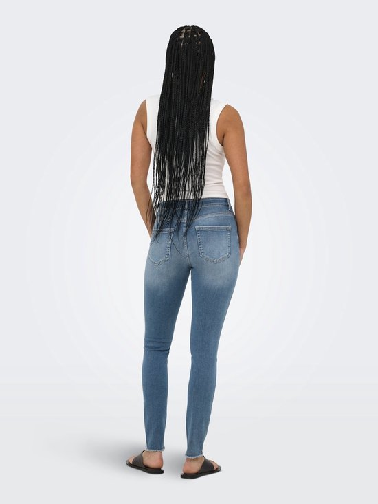 Model van achteren gezien, draagt een blauwe skinny fit jeans met middelhoge taille en rafels aan de zoom.