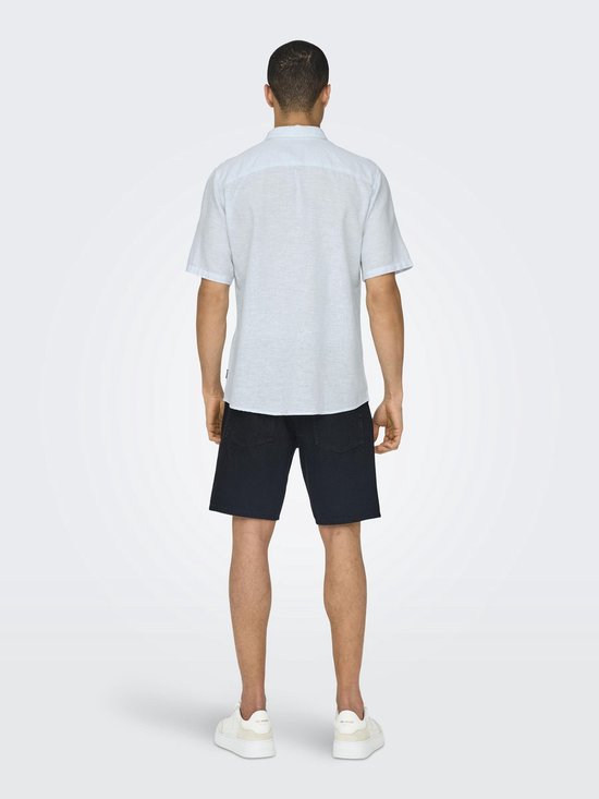 Man die een lichtblauw kortgerokt overhemd draagt, met zwarte shorts.