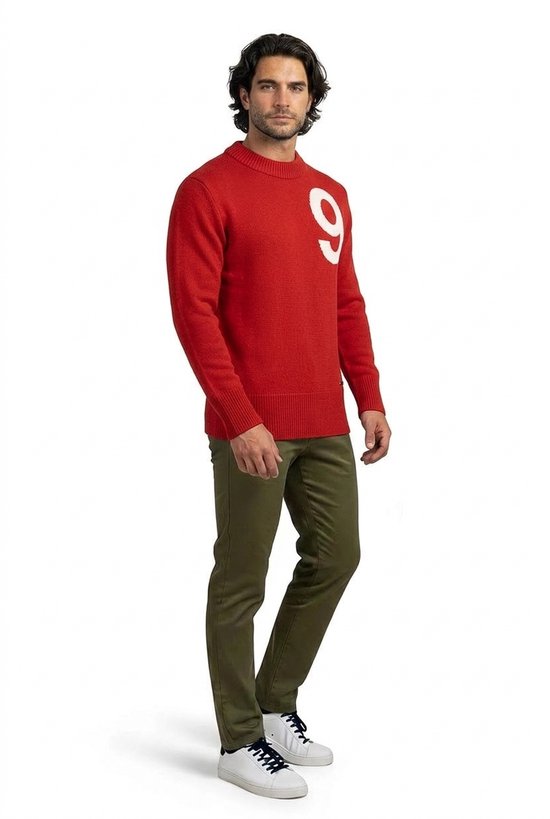 Man in een rode trui met witte 9, gedragen met een olijfgroene broek.