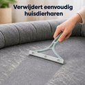 Une main utilise un dépilateur vert clair pour enlever les poils d'animaux d'un canapé en tissu.