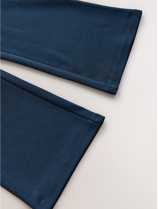 Close-up van de onderkant van twee donkerblauwe broeken, met een zoom met dubbele stiksels.