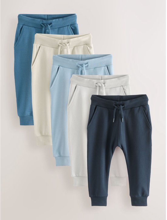 Set van vijf joggingbroeken in diverse blauwe en beige tinten, elk met een elastische taille en trekkoord.