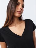 Model draagt een zwart T-shirt met V-hals en korte mouwen.
