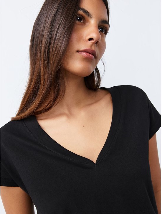 Model draagt een zwart T-shirt met V-hals en korte mouwen.