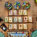 Bovenaanzicht van het spelbord De Kwakzalvers van Kakelenburg met spelborden, kaarten, fiches en drie glazen schalen met fiches.