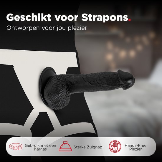 Zwarte realistische dildo met zuignap, bevestigd aan een harnas voor handsfree gebruik.