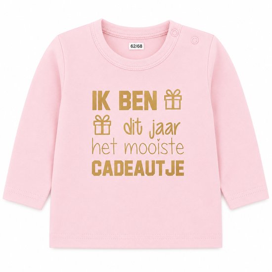 T-shirt bébé rose pâle à manches longues avec le texte doré 'IK BEN dit jaar het mooiste CADEAUTJE' et des symboles de cadeau.