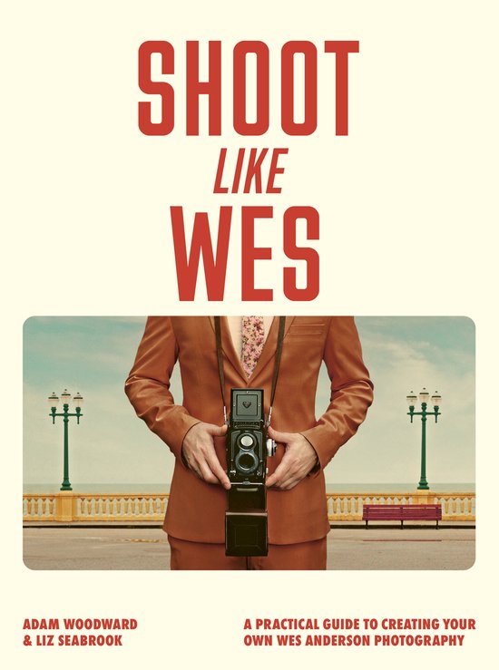 Couverture du livre "SHOOT LIKE WES". Un homme en costume marron avec une cravate à fleurs tient un appareil photo.