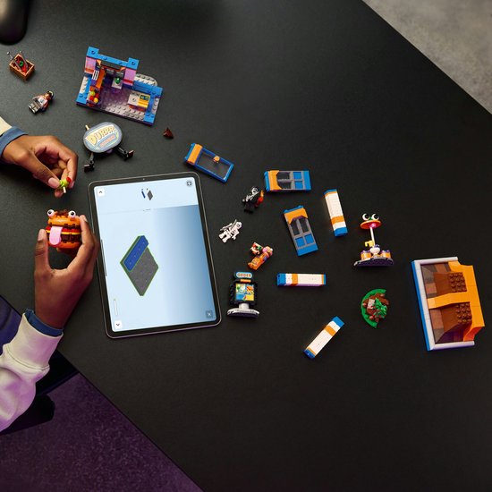 Enfant construisant du LEGO Fortnite avec une tablette, des figurines et des pièces du restaurant
