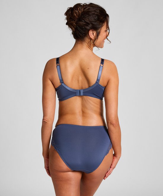 Model van achteren gezien, draagt blauwe bh met stippen en kanten details, en slip met kanten rand.