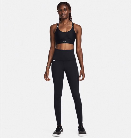 Model draagt een zwarte sportbeha en een zwarte legging met hoge taille. De bandjes van de sportbeha hebben tekst.