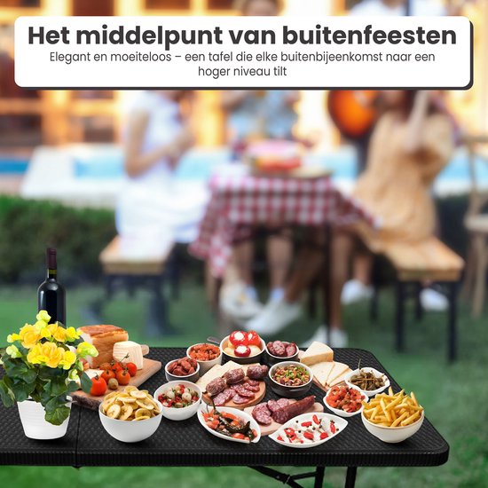 Een zwart tafelblad met rotan-look, vol met eten, op een buitenfeest.