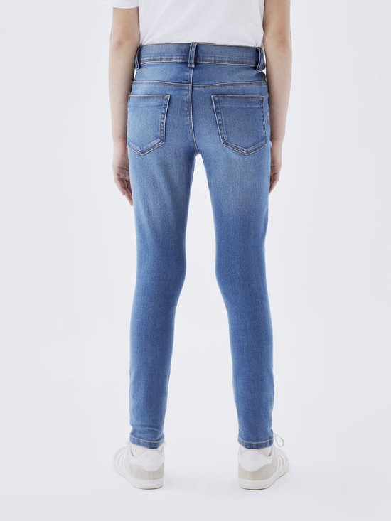 Meisje in een spijkerbroek met skinny fit in medium blauwe denim, gezien vanaf de achterkant.