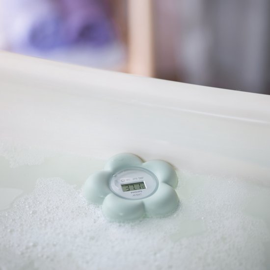 Lichtgroene Philips Avent bloemvormige thermometer in badwater met zeepbellen. Geeft 37.1°C weer.