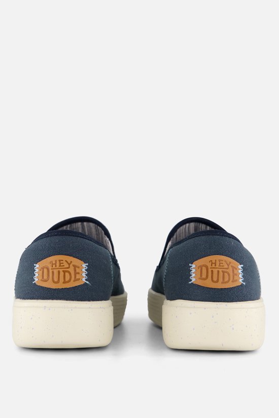Vue arrière de deux mocassins HEYDUDE bleus avec semelles blanches et le logo 'HEY DUDE'.