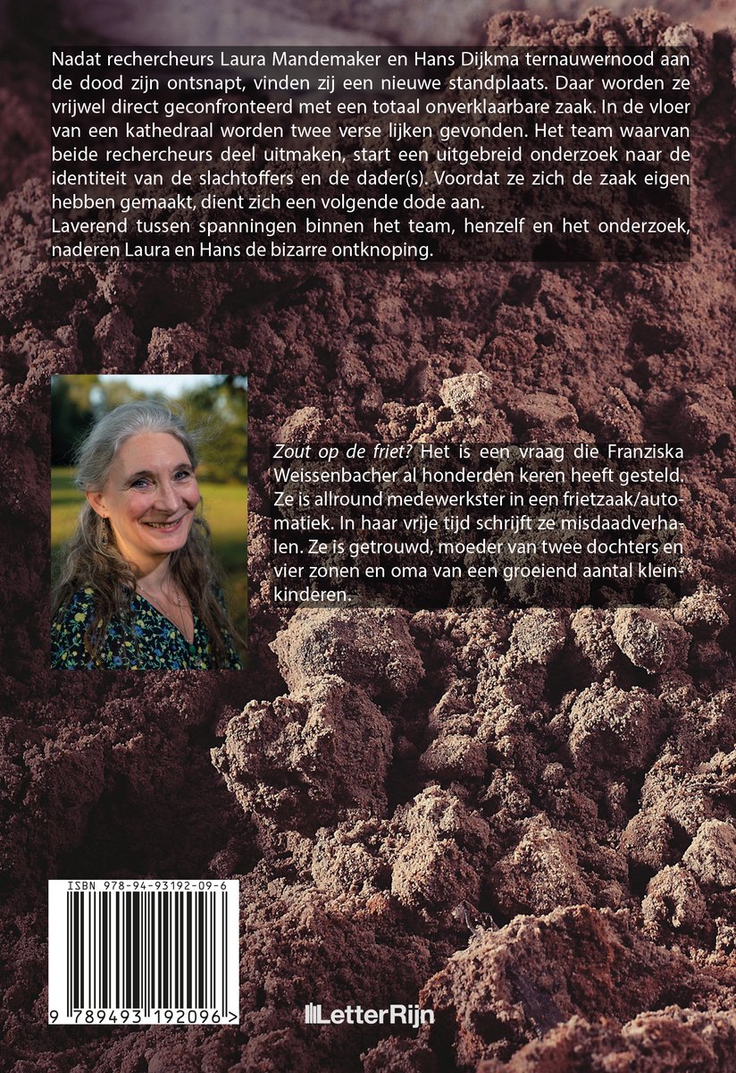 Portret van een lachende vrouw met grijs haar en een bloemenblouse, tegen een achtergrond van bruine aarde.