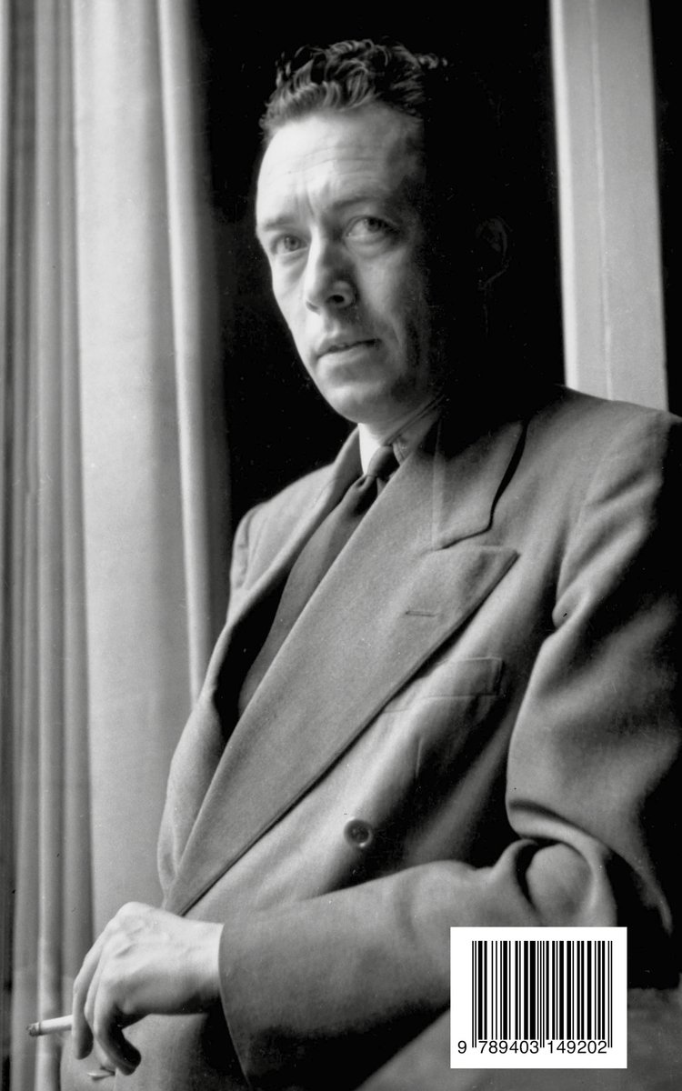 Portret van Albert Camus in driedelig pak, met een sigaret in zijn hand, leunend op een vensterbank.