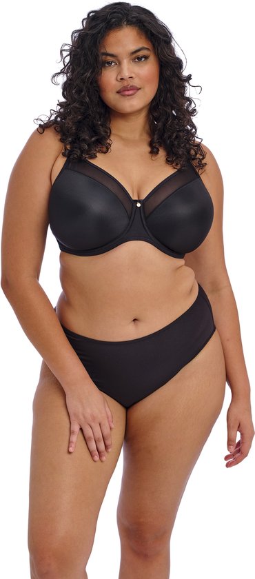 Model met krullend haar draagt een zwarte beha met mesh-details en een bijpassende zwarte slip.