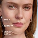 Close-up van een gezicht met tekst: APPLY TO FACE & NECKLINE, MASSAGE INTO SKIN, REAPPLY REGULARLY.