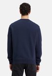 Achterkant van donkerblauwe sweater met ronde hals, gedragen door man met zwarte jeans.