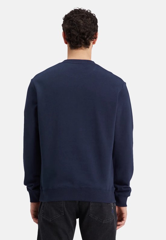 Achterkant van donkerblauwe sweater met ronde hals, gedragen door man met zwarte jeans.