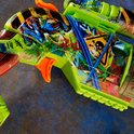 Detail van een groene speelgoedblaster met oranje en rode verfspatten, camouflageprint en skull-motief.