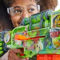 Meisje met beschermende bril houdt een felgroene Nerf Zombie Corrupter blaster vast, versierd met zombie-thema afbeeldingen.