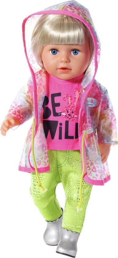 Pop met blond haar en staartjes, roze T-shirt 'BE WILD', regenjas met luipaardprint, knalgroene broek en zilveren laarsjes.