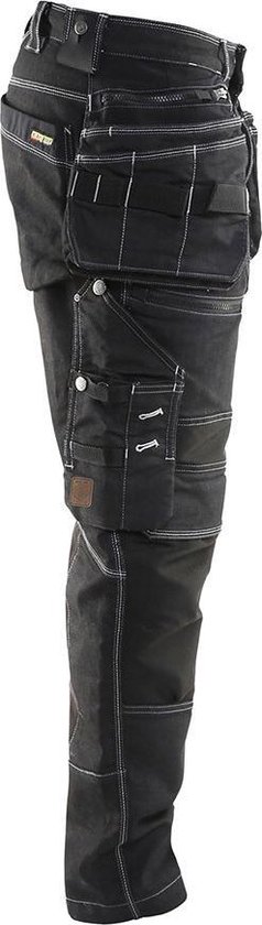 Zijzicht van zwarte werkjeans met vele zakken, gespen en witte stiksels.