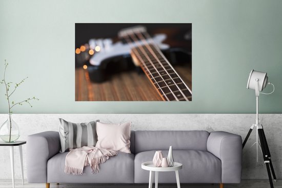 Une guitare basse repose sur une table Poster 120x80 cm - Tirage photo sur Poster (décoration murale salon / chambre)