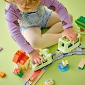 Enfant jouant avec un train et une gare DUPLO; les trains sont vert clair avec des détails.