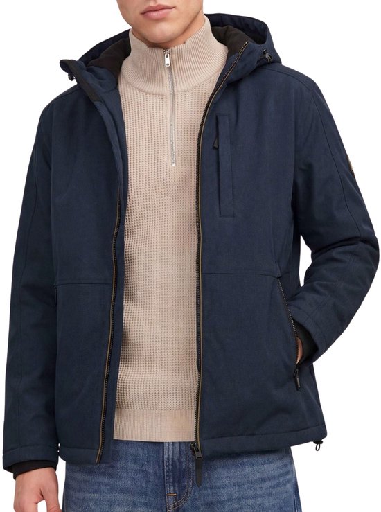 Model draagt openstaande donkerblauwe jas met rits. Beige coltrui en jeans.