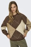 Model draagt bruine trui met ruitpatroon in gebroken wit en beige, met groene broek.