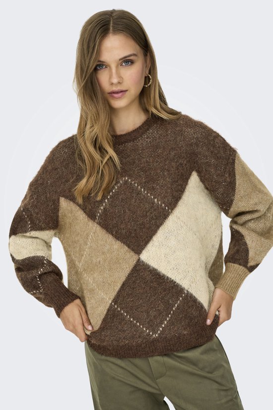 Model draagt bruine trui met ruitpatroon in gebroken wit en beige, met groene broek.