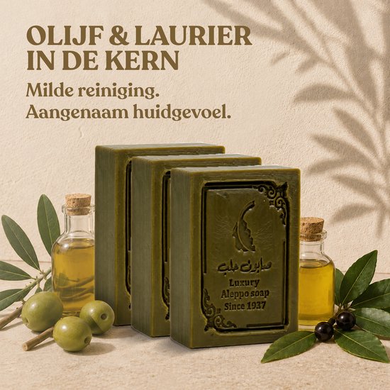 Drie groene zeepblokken op een steen, met olijven, laurierbladeren en flesjes olijfolie.