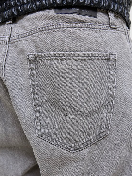 Close-up van de achterkant van grijze jeans met een merklogo op de zak.