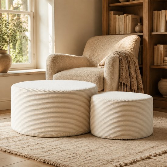Twee beige gestreepte ronde hockers voor een fauteuil in een gezellige woonkamer.