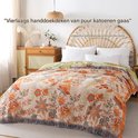 Gedrapeerd over een bed met rotan hoofdeinde, met een kleurrijke botanische print en franjes.