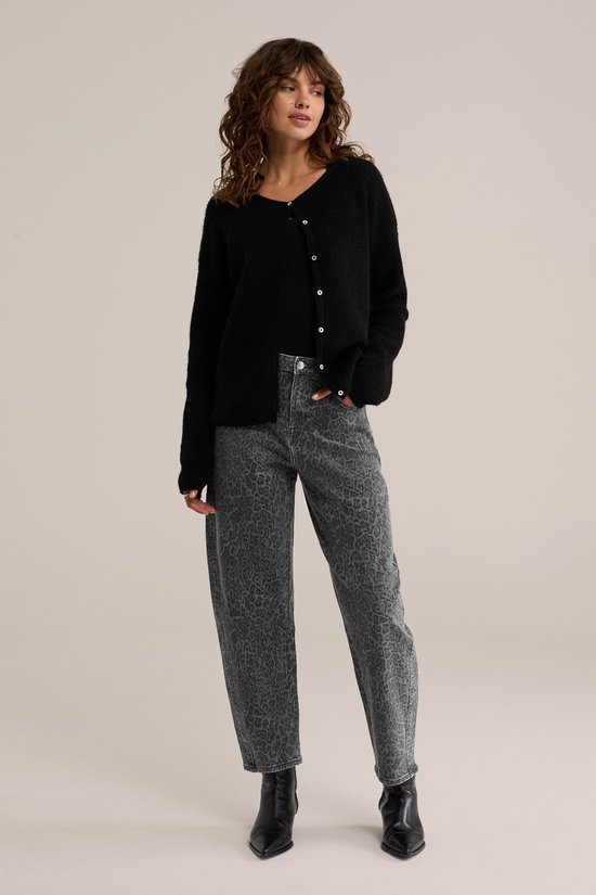 Model met een zwarte gebreide cardigan en een grijze jeans met luipaardprint.