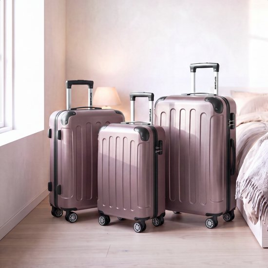 Drie roze koffers in een slaapkamer, een lichtroze deken op het bed.